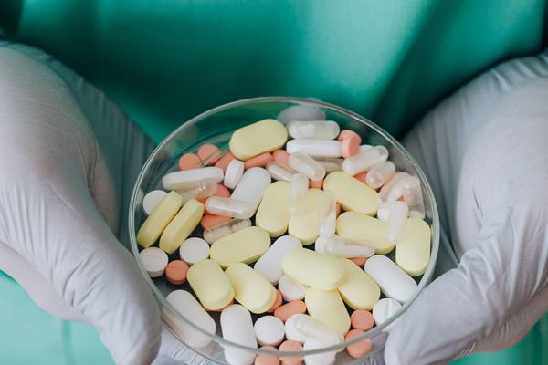 Hands holding a dish of assorted tablets